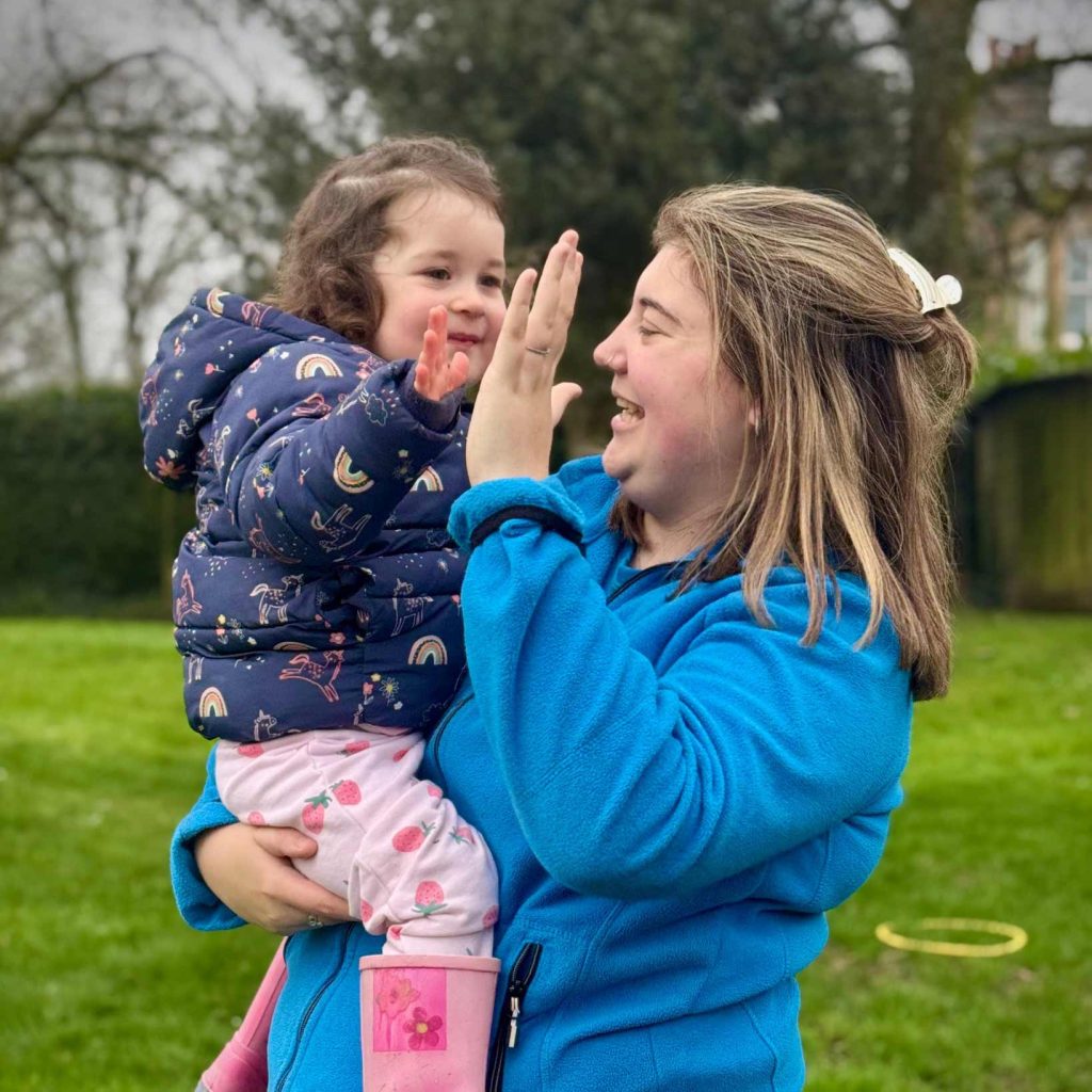 Sunny Days Melissa high fiving a small child wearing pink wellies